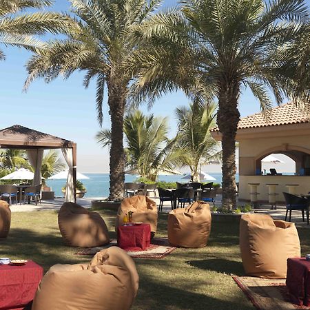 Al Raha Beach Resort & Spa Abu Dhabi Restaurant foto The photo depicts a beautiful outdoor setting with several elements of relaxation and leisure. In the foreground, there are large, comfortable bean bag chairs arranged on a grassy area, accompanied by low tables. Surrounding this seating area are tal